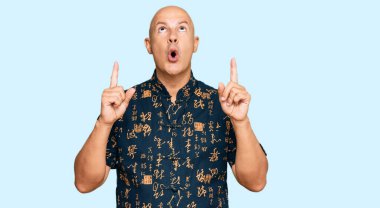 Orta yaşlı, kel, sıradan kıyafetler giyen, şaşkın ve şaşırmış bir halde yukarı bakıp, parmaklarıyla işaret ediyor ve kollarını kaldırıyordu.. 