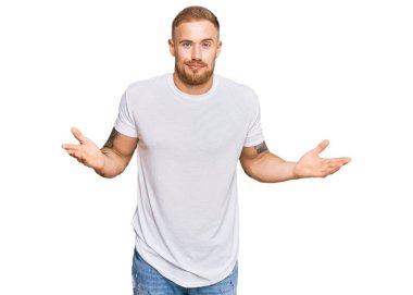 Sıradan kıyafetler giyen, elleri ve kolları havada, kafası karışmış genç İrlandalı bir adam. şüphe kavramı. 