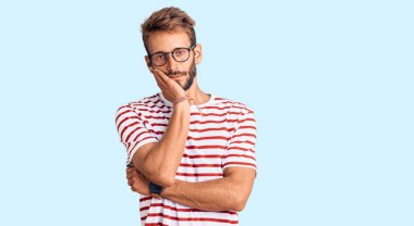 Sakallı, sıradan kıyafetler ve gözlükler takan yakışıklı sarışın adam kollarını kavuşturup depresyondan sıkılmış ve yorgun görünüyor.. 