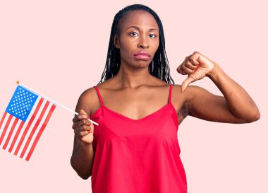 Amerika Birleşik Devletleri bayrağını elinde tutan Afro-Amerikalı genç bir kadın. Kızgın yüzlü, negatif işaretli, başparmakları aşağıda, reddedilme kavramından hoşlanmadığını gösteren. 
