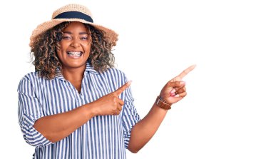 Genç Afrikalı Amerikalı, iri yarı, yaz şapkalı, gülümseyen ve kameraya bakan bir kadın.. 