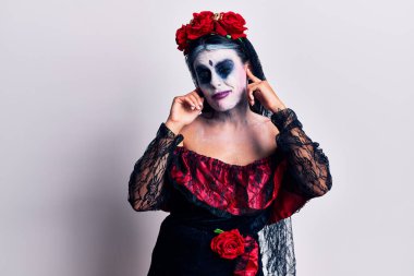 Meksika usulü makyaj yapan genç bir kadın yüksek sesli müzik sesi için kulaklarını parmaklarıyla kapatıyor. sağır kavramı. 