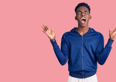 Genç Afro-Amerikan erkek spor kıyafetleri giyiyor deli gibi bağırıyor ve agresif bir ifadeyle bağırıyor ve kollarını kaldırıyor. hüsran kavramı. 