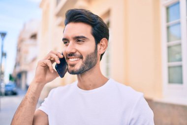 Genç İspanyol adam gülümsüyor. Şehirdeki akıllı telefondan konuşuyor..