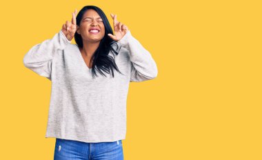 Uzun saçlı, günlük kıyafetler giyen, umut ve gözlerin kapalı bir şekilde gülümseyerek el hareketi yapan İspanyol bir kadın. Şans ve batıl inançlar. 