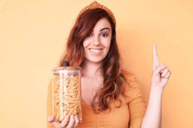 Genç ve güzel bir kadın elinde makarna kavanozuyla gülümseyen bir fikir ya da soru işareti yapan mutlu yüzlü, bir numara. 