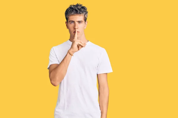 唇に指で静かになるように頼むカジュアルな白いTシャツを着た若いハンサムな男 沈黙と秘密の概念 — ストック写真
