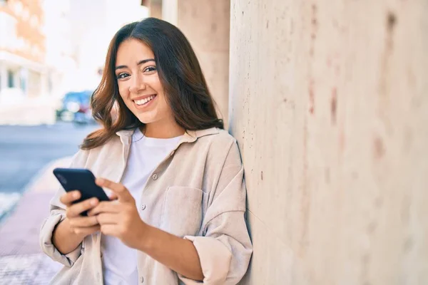 若いヒスパニック系の女性は 市内でスマートフォンを使用して幸せな笑顔 — ストック写真