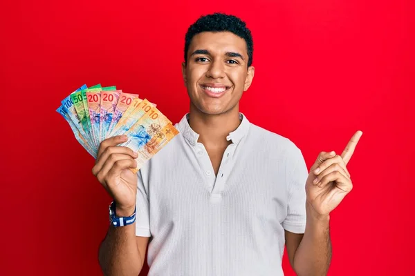 Joven Árabe Sosteniendo Billetes Franco Suizos Sonriendo Feliz Señalando Con —  Fotos de Stock