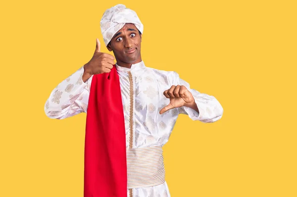 伝統的なシャーワニを身に着けているアフリカのハンサムな男は 親指を上下に行う服を見て 意見の相違や合意表現 狂気の葛藤 — ストック写真