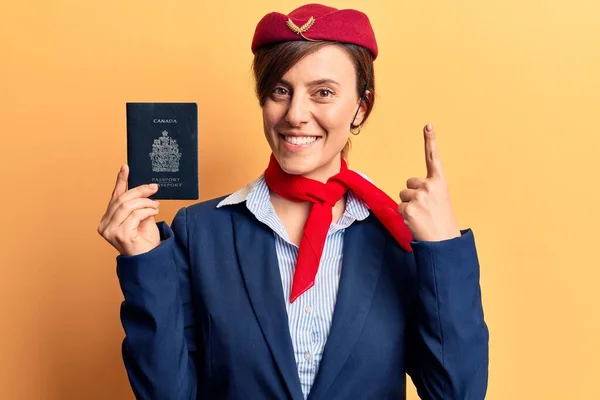 Молодая Красивая Женщина Униформе Стюардессы Держит Канадский Паспорт Улыбаясь Идеей — стоковое фото