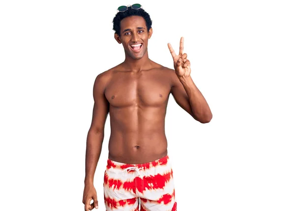 身穿泳衣 戴着太阳镜的非洲帅哥 带着自信和快乐的笑容 用手指指指着二号 — 图库照片
