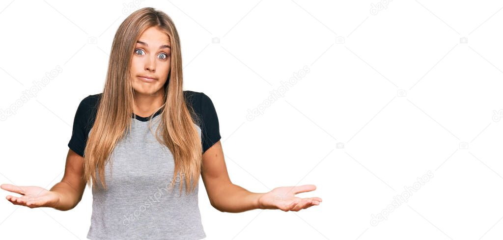 Young blonde woman wearing casual clothes clueless and confused expression with arms and hands raised. doubt concept. 