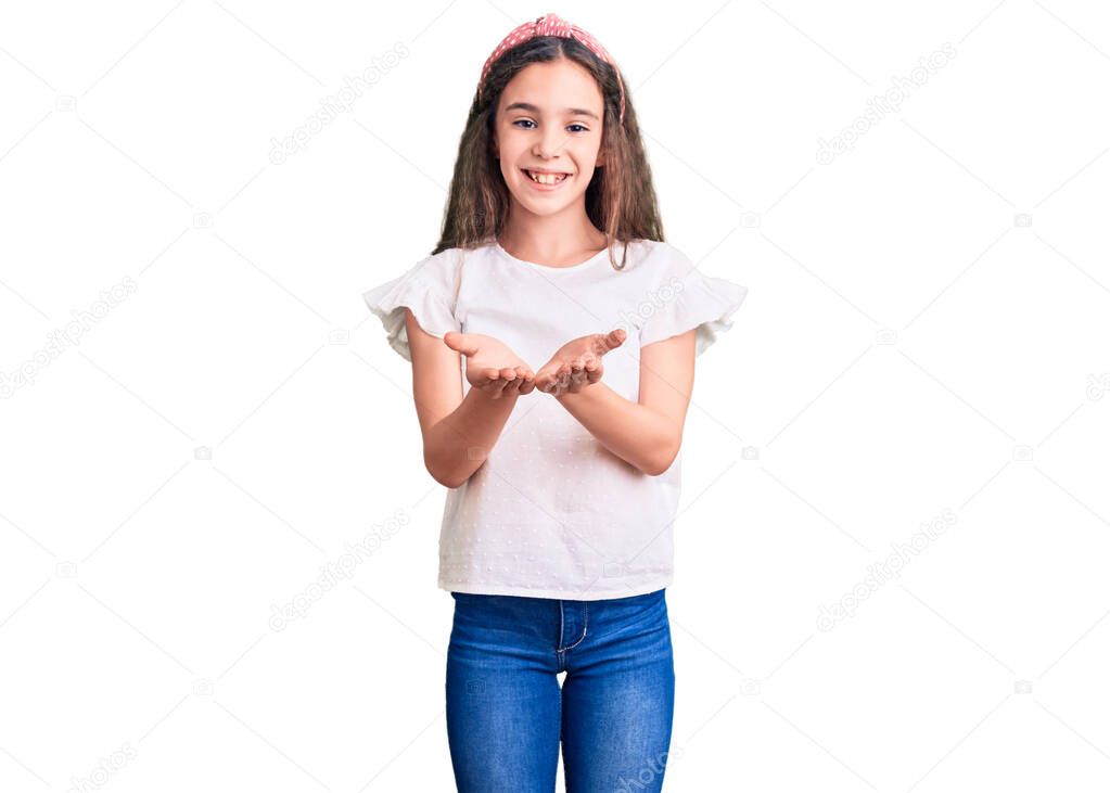 Cute hispanic child girl wearing casual white tshirt smiling with hands palms together receiving or giving gesture. hold and protection 