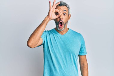 Orta yaşlı, gri saçlı, sıradan kıyafetler giyen, şaşırmış yüzüyle şaşırmış, parmaklarından bakan bir adam. İnançsız ifade. 