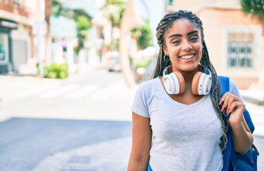 Genç Afrikalı Amerikalı öğrenci kampüste mutlu gülümsüyor.