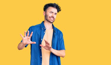 Gündelik kıyafetler giyen genç İspanyol adam tiksinti ifadesi takındı, tiksinti tepkisi yüzünden tiksinti ve korku dolu bir ifade takınıyordu. Eller havada. 