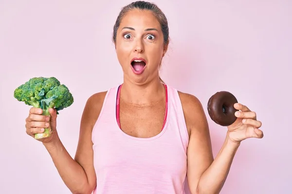 Donna Ispanica Mezza Età Con Broccoli Ciambelle Cioccolato Spaventati Scioccati — Foto Stock