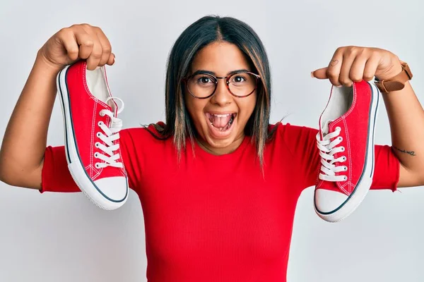 Joven Chica Latina Sosteniendo Zapatos Casuales Rojos Celebrando Loco Sorprendido —  Fotos de Stock