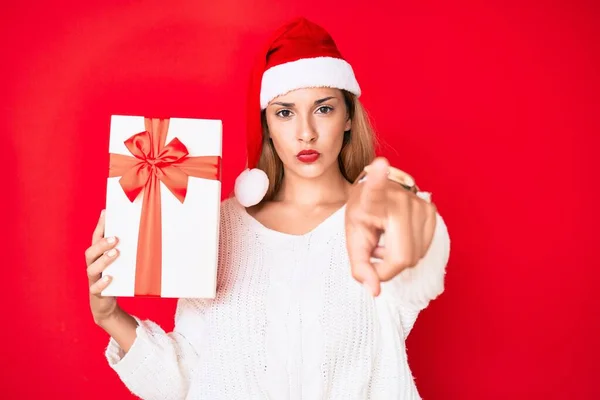 크리스마스 모자를 선물을 카메라를 손가락으로 가리키는 여자와 당신에게 자신감 보이는 — 스톡 사진
