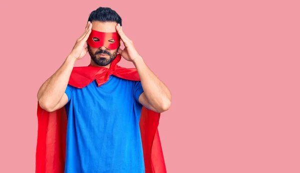 痛みや片頭痛のために必死に頭痛やストレスに苦しんでスーパーヒーローの衣装を着て若いヒスパニック系の男 手を頭に — ストック写真