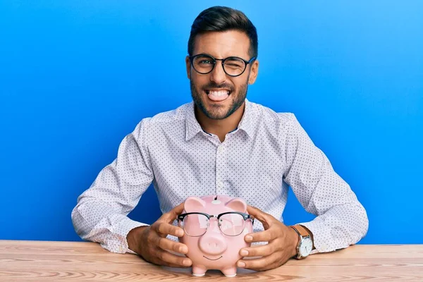 Fešák Hispánec Muž Drží Prasátko Banky Brýlemi Vyčnívat Jazyk Šťastný — Stock fotografie