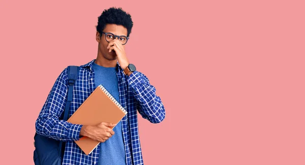 Joven Afroamericano Con Mochila Estudiante Sosteniendo Libro Oliendo Algo Apestoso —  Fotos de Stock