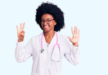Genç Afro-Amerikan kadın doktor önlüğü ve steteskop giyiyor. Sekiz numaralı parmaklarıyla işaret ediyor. Kendinden emin ve mutlu bir şekilde gülümsüyor.. 