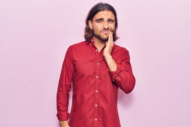 İş kıyafetleri giymiş genç bir adam diş ağrısı ya da diş hastalığından dolayı acı dolu bir ifadeyle ağıza dokunuyor. dişçi 