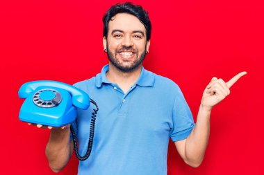 Antika telefon tutan genç İspanyol adam gülümsüyor mutlu bir şekilde elini ve parmağını yana uzatıyordu. 