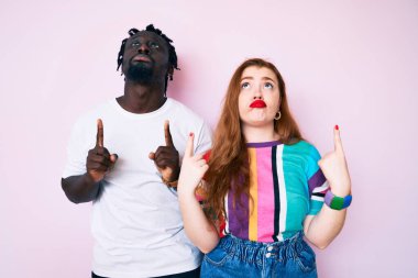 Irklar arası çift gündelik giysiler giyip üzgün ve üzgün görünüyor, parmaklarıyla yön gösteriyor, mutsuz ve depresif.. 