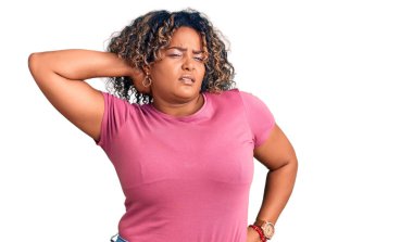 Genç Afro-Amerikan artı cüsseli kadın günlük kıyafetler giyiyor boyun ağrısı çekiyor, boynuna elle dokunuyor, kas ağrısı çekiyor. 