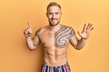 Mayo giyen genç, beyaz bir adam altı numaralı parmaklarıyla gösteriş yapıyor ve gülümsüyor. Kendinden emin ve mutlu.. 