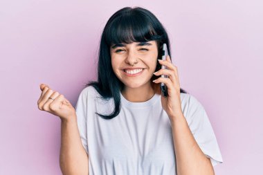 Genç İspanyol kız telefonda konuşuyor gururla bağırıyor, zaferi kutluyor ve kollarını kaldırarak heyecanlanıyor. 