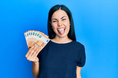 Elinde 50 avroluk banknotlar tutan genç ve güzel bir kadın komik bir ifadeyle dilini dışarı çıkarıyor. duygu kavramı. 