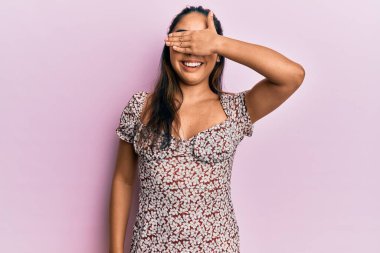 Gündelik kıyafetler giyen, gülümseyen ve el ele gülen genç Latin kadın şaşırtmak için gözlerini kapatıyor. kör kavram. 