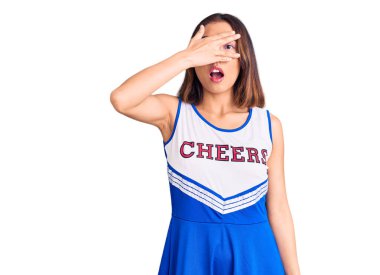 Genç, güzel Çinli kız amigo üniforması giyiyor. Şoka girip yüzünü ve gözlerini kapıyor. Utanmış bir ifadeyle parmaklarının arasından bakıyor.. 