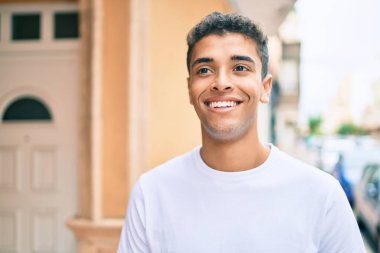 Genç Latin adam gülümseyerek şehirde mutlu mesut yürüyor..