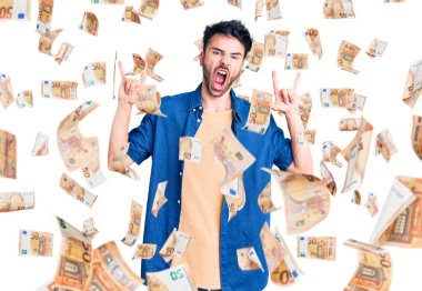 Latin asıllı genç adam, gündelik kıyafetler giyip çılgın bir ifadeyle bağırıyor ve elleri havada rock sembolü yapıyor. Müzik yıldızı. ağır kavram.