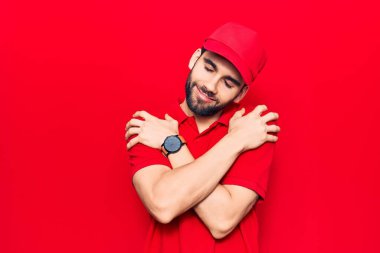 Sakallı, polo giyen, şapkalı, mutlu, pozitif ve kendinden emin bir şekilde kendine sarılan yakışıklı bir adam. Sevgi ve özgüven. 