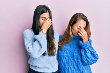 Anne ve kızının yün kazak giydiği İspanyol ailesi yorgun burunlarını ve gözlerini ovuşturup yorgunluk ve baş ağrısı hissediyorlar. Stres ve hüsran kavramı. 