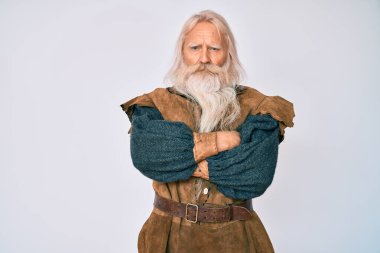 Gri saçlı, uzun sakallı, Viking kostümü giyen, kuşkucu ve gergin, yüzünde çapraz kollu tasvip etmeyen yaşlı bir adam. negatif kişi. 