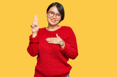 Kısa saçlı, sıradan süveter giyen ve gülümseyen gözlüklü, elleri göğsünde ve parmakları havada küfür eden, sadakat yemini eden genç, İspanyol bir kadın. 