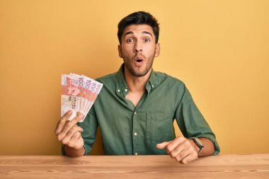 Hong Kong doları tutan yakışıklı genç adam banknotlar korkmuş ve hayrete düşmüştü. 