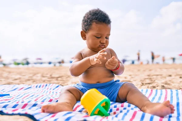 愛らしいアフリカ系アメリカ人の幼児はおもちゃで遊んでいます砂の上に座ってビーチ — ストック写真