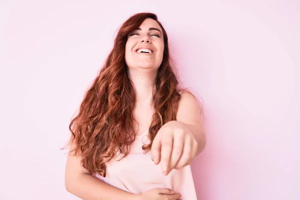 Young beautiful woman wearing casual clothes laughing at you, pointing finger to the camera with hand over body, shame expression