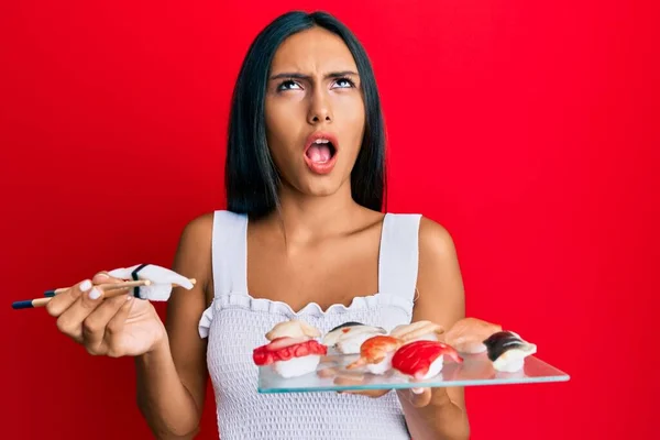 Joven Morena Comiendo Sushi Pez Mantequilla Usando Palillos Enojado Loco —  Fotos de Stock