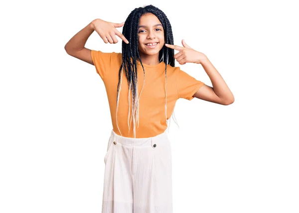 かわいいアフリカ系アメリカ人の女の子は 陽気で笑顔を見せ 指の歯と口で指してカジュアルな服を着ています 歯の健康の概念 — ストック写真