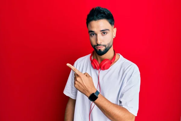 Joven Con Barba Escuchando Música Usando Auriculares Apuntando Con Dedo — Foto de Stock