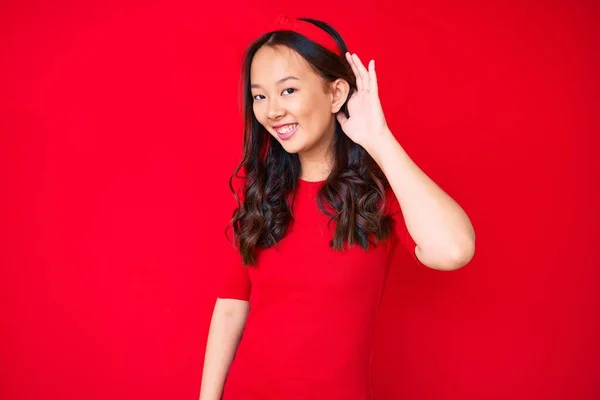 年轻美丽的中国姑娘 身穿休闲装 面带微笑 亲耳听谣言或流言蜚语 聋的概念 — 图库照片